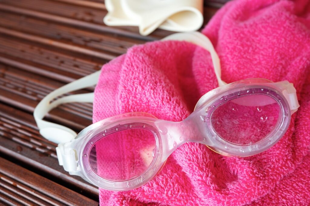 Swim goggles, towel, and a swim cap are displayed.