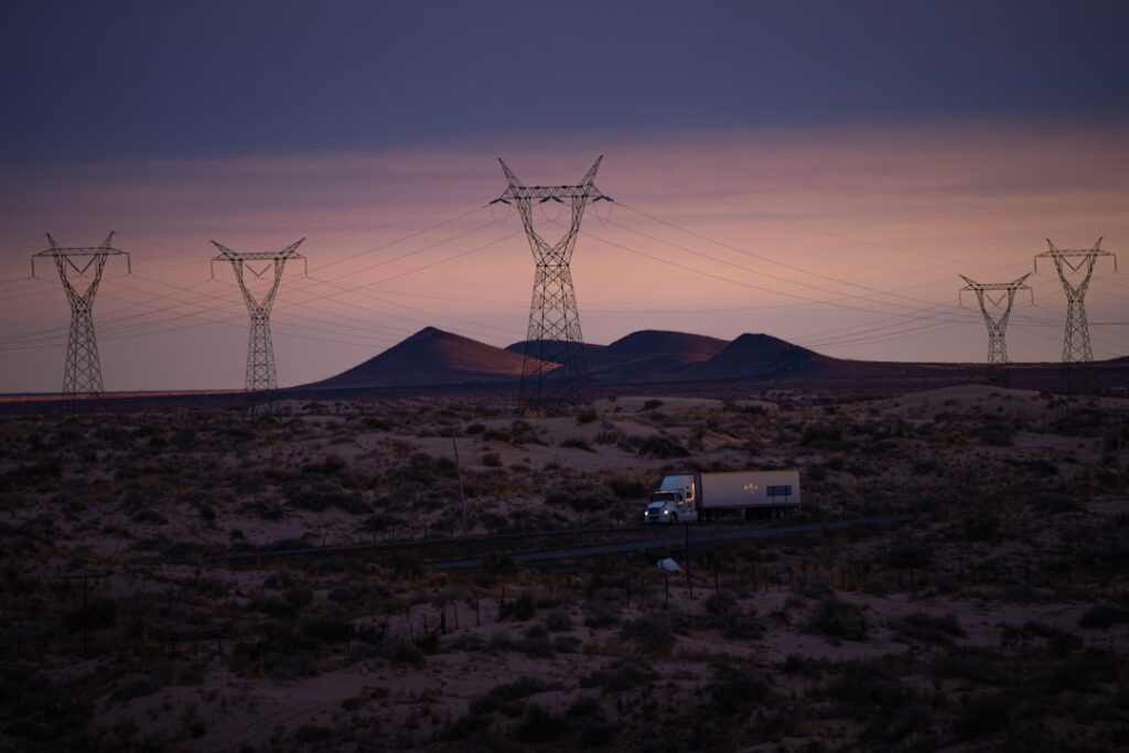Power lines and truck in desolate landscape at dusk