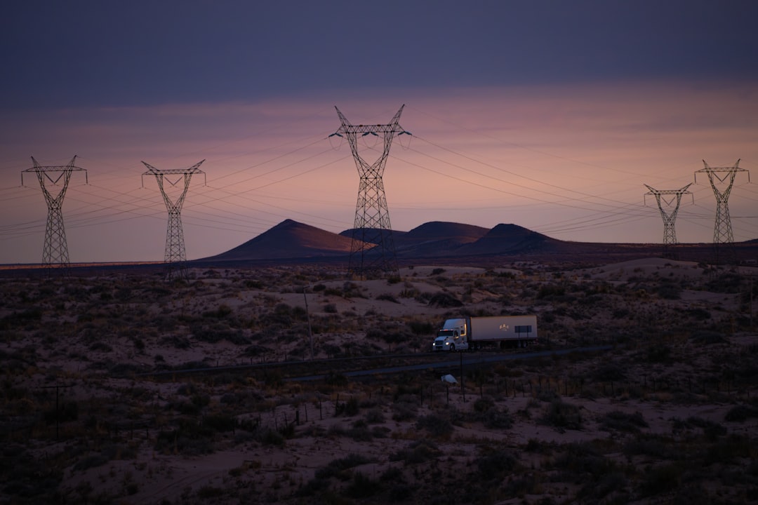 Power lines and truck in desolate landscape at dusk